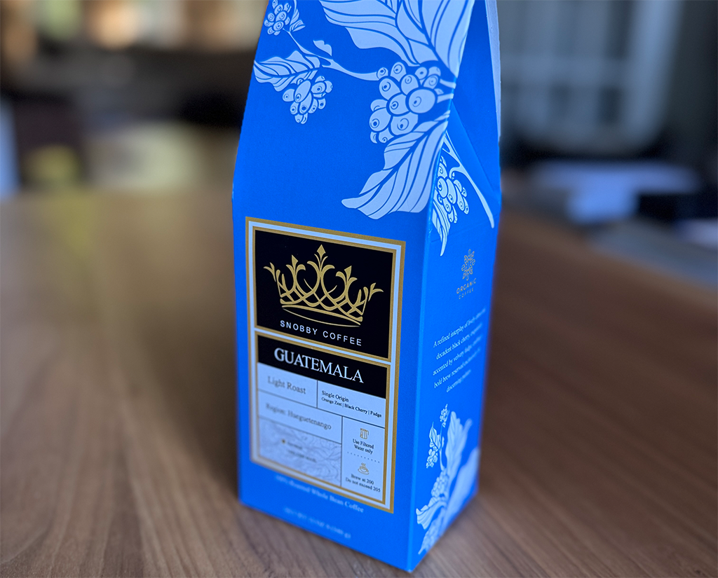 Blue coffee packaging with 'Guatemala' branding on a wooden surface