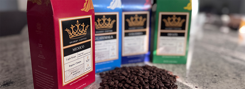 Three coffee boxes with visible branding on a surface with coffee beans.